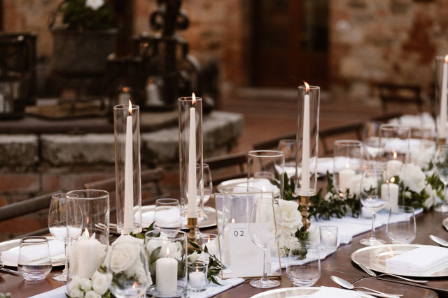 Elegant reception table with taper candles, roses and greenery