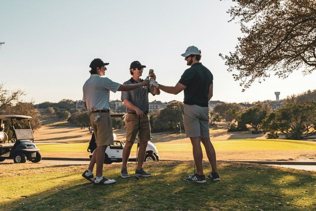 Dre Männer stoßen auf einem Golfplatz mit einem Bier an