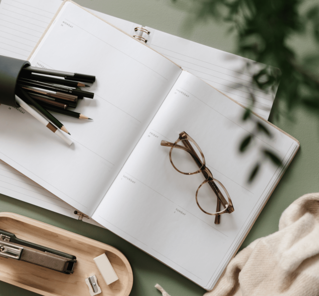 Kalender auf grünem Tisch mit Stiften ausgeleert darauf