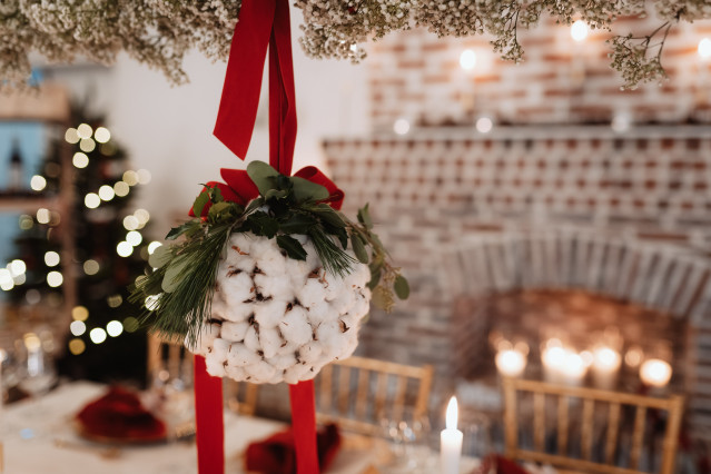 Mistelzweig mit weißer Baumwolle hängt über einem weihnachtlich gedeckten Tisch