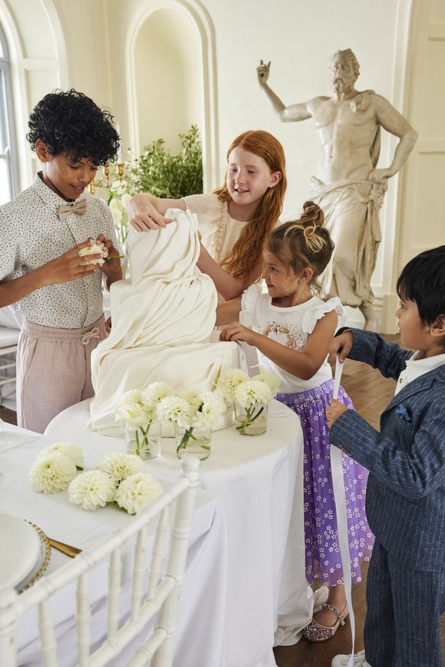 Kinder stehen um Hochzeitstorte herum