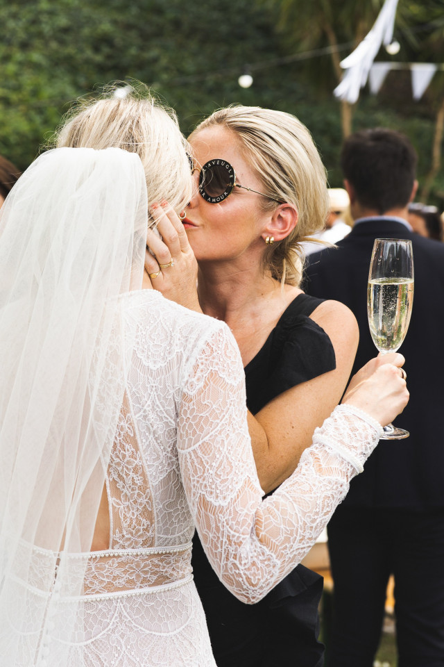 Donna che abbraccia la sposa, che ha un bicchiere di champagne in mano