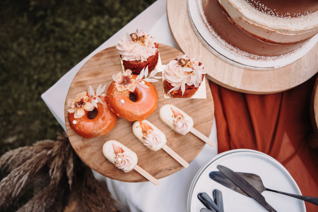 Donuts mit orangener Glasur auf einem Holzbrettchen