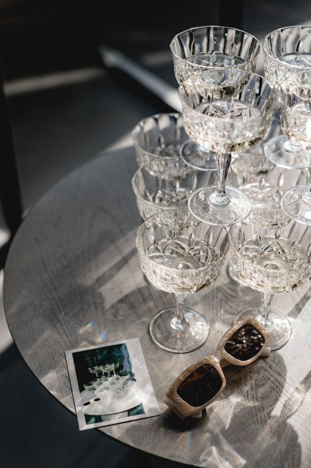 Champagnergläser und Polaroid Foto neben einer Sonnenbrille auf einem Tisch
