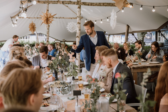 gasten onder een tent bij bruiloft