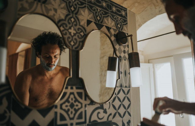The groom gets ready in front of the mirror in a relaxed moment before the wedding.