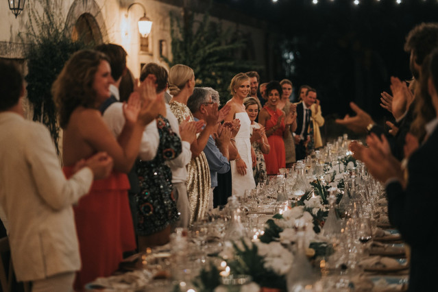 Guests stand applauding along the festively set banquet table.