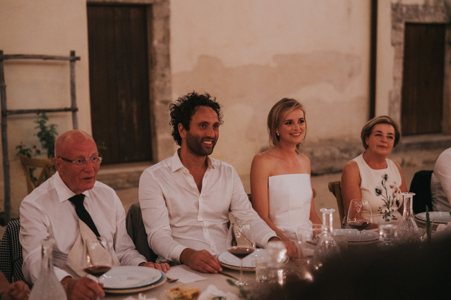 The couple and their guests gather at a long, beautifully set dinner table.