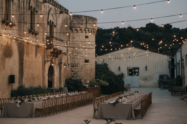 Elegantly set party tables glow under string lights at an outdoor reception.
