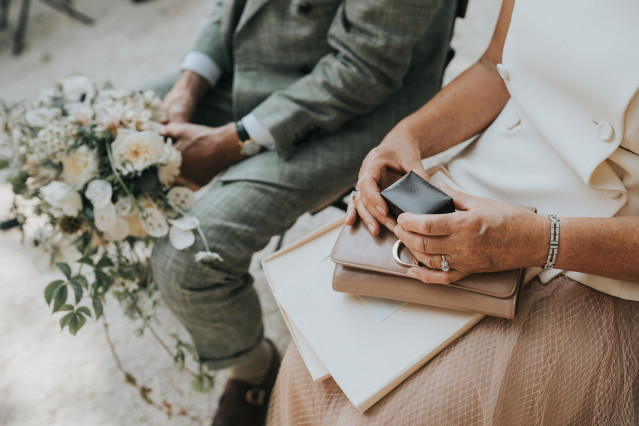 A detail photo of a seated couple's hands resting together with a bouquet.