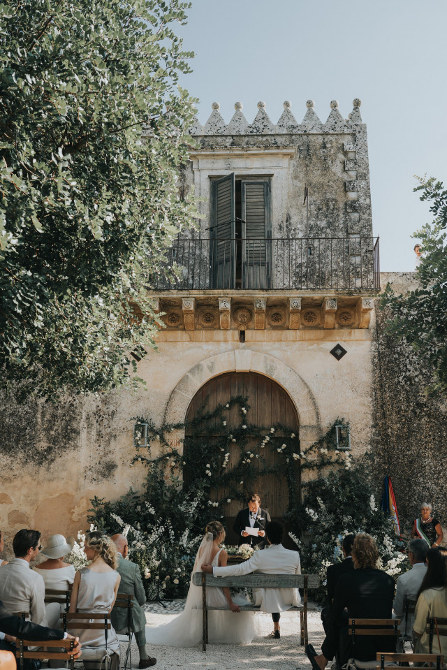 An overview of the outdoor ceremony set before a large floral arch.