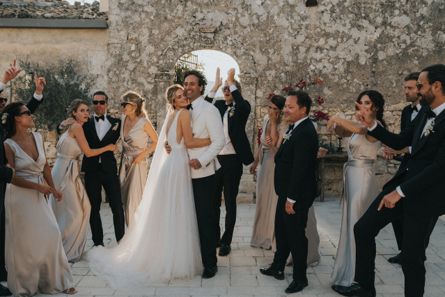 The couple shares a kiss as cheering guests look on at their celebration.