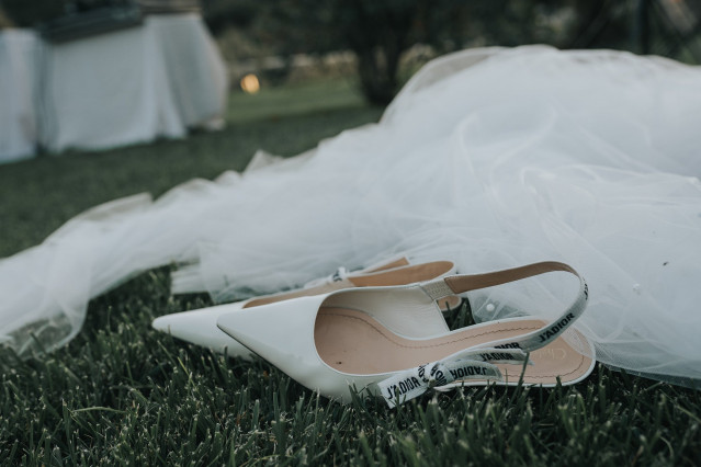 A detail photo of white bridal shoes resting in the grass.