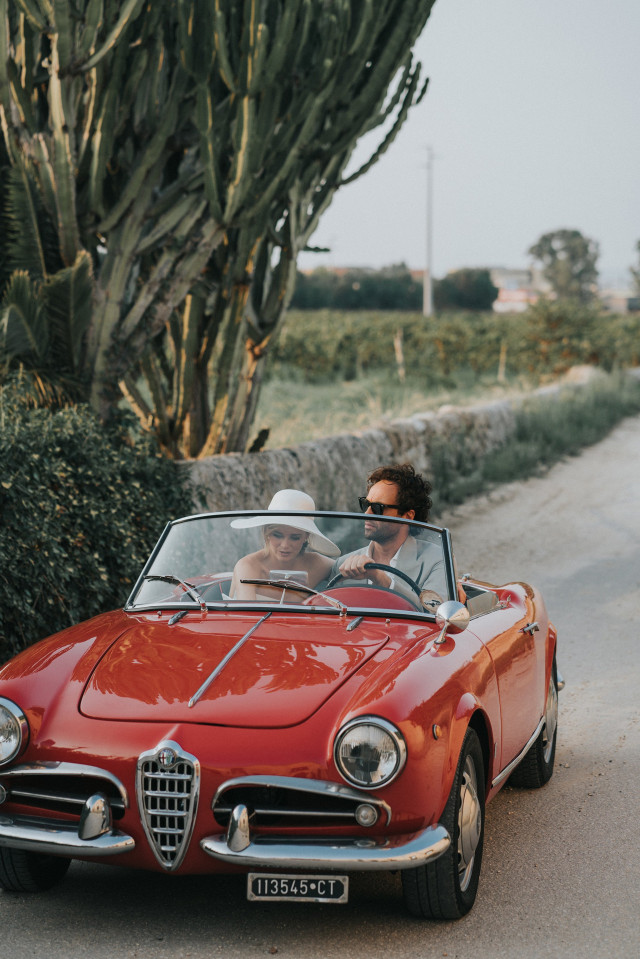 The couple rides in a red classic Alfa Romeo convertible after the wedding.