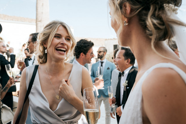 A laughing female guest with a champagne glass chats warmly at the party.