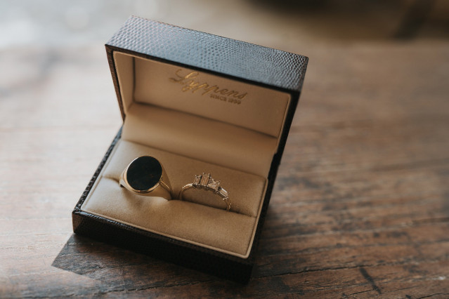 A close-up of an opened ring box presented at a wedding.