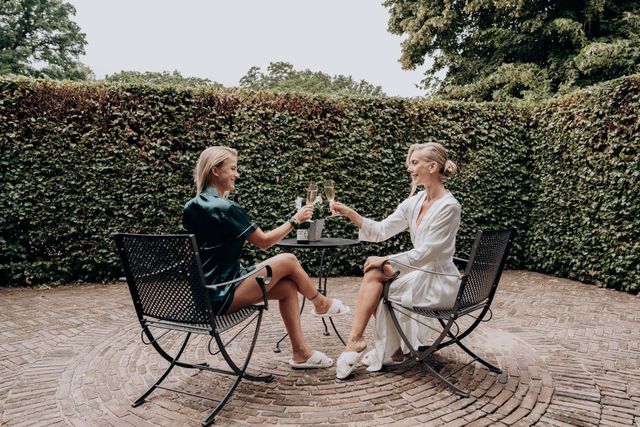 twee vrouwen die aan een tafel zitten met wijnglazen in hun handen
