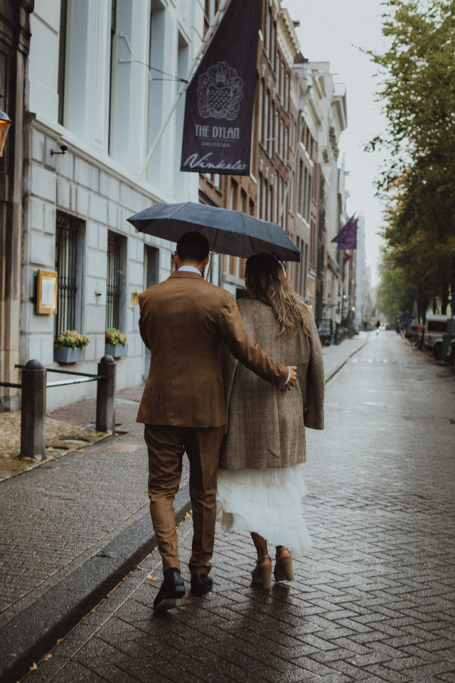 Braut und Bräutigam unter Regenschirm laufen 