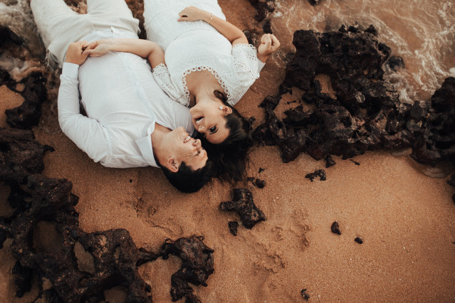 Frau und Mann liegen am Strand und lachen sich an