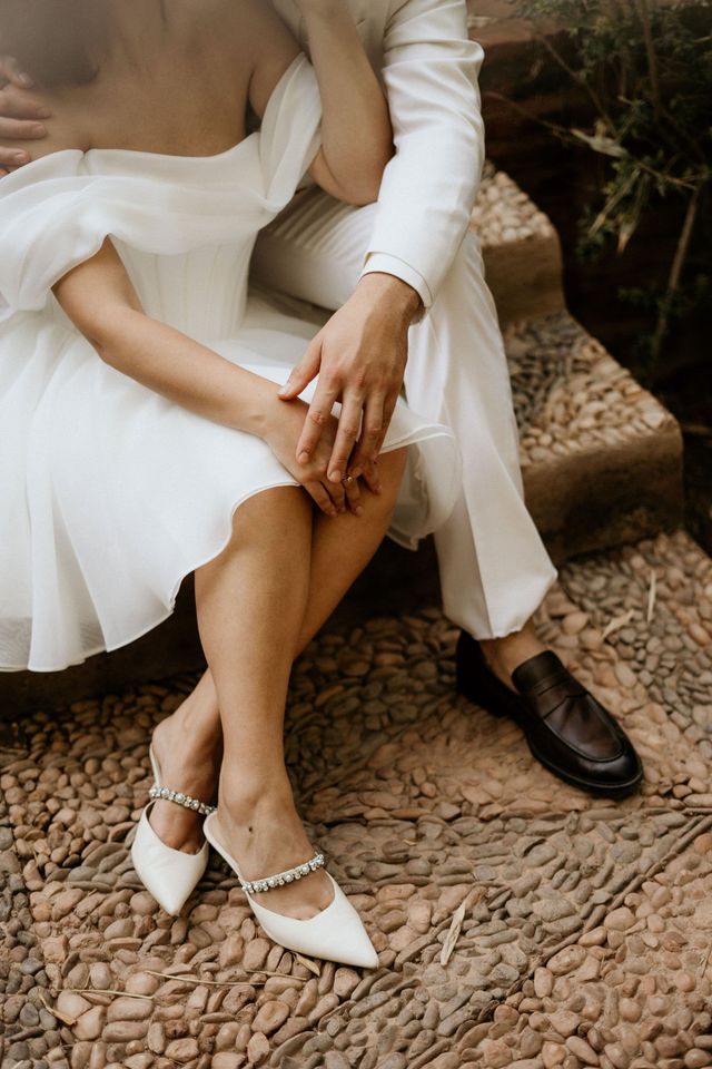 Gros plan sur des chaussures de mariée avec cristaux et les mains des mariés avec l'alliance