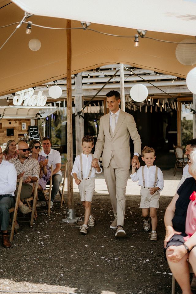 Groom walking down the aisle with two young ring bearers