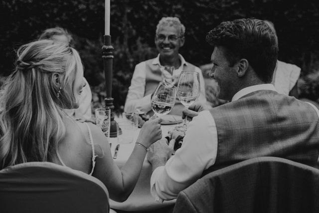Een opgedekte dinertafel die buiten staat en versiert is met vaasjes en witte bloemen.