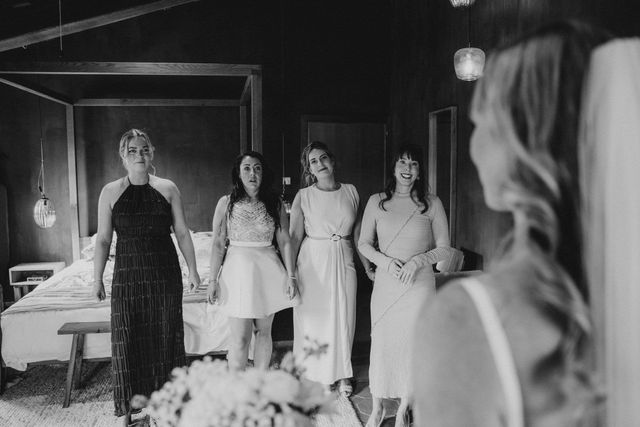 Bridesmaids react with joy as they see the bride in her wedding gown for the first time.