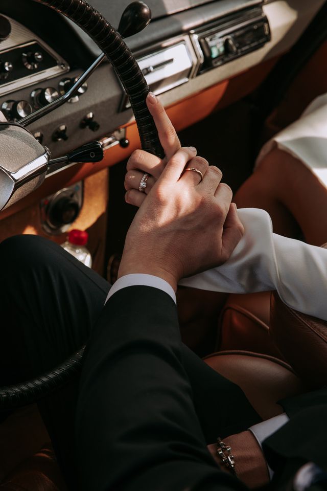 bruidspaar houdt hand vast in auto
