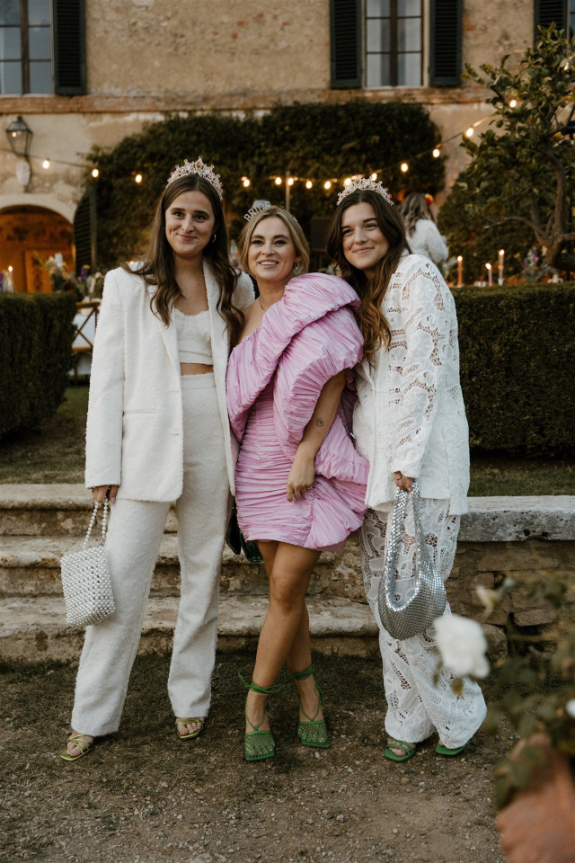drie vrouwen in witte en roze outfits poseren voor een foto