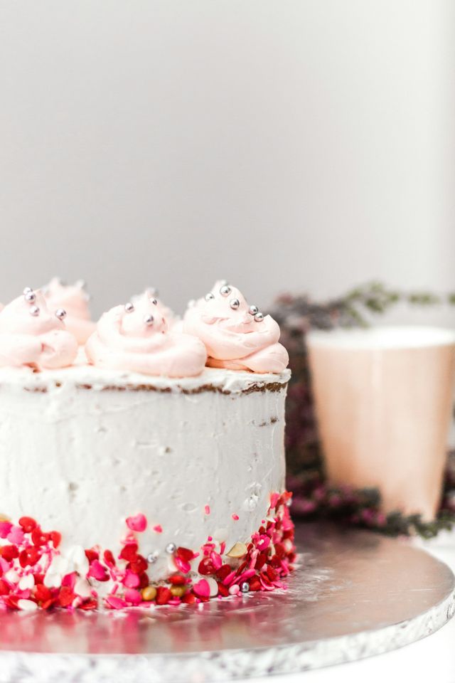 Kleine weiße Torte mit rosa Sahne und silbernen Perlen