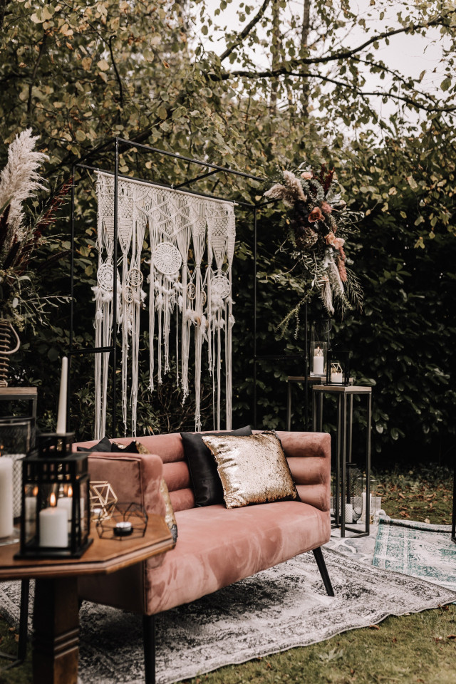 Dunkle Bohemian Dekoration vor einer Couch mit einem Makramee Backdrop
