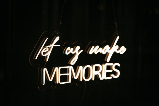 Neon Schild mit Aufschrift "Let us make memories" vor einem schwarzen Hintergrund