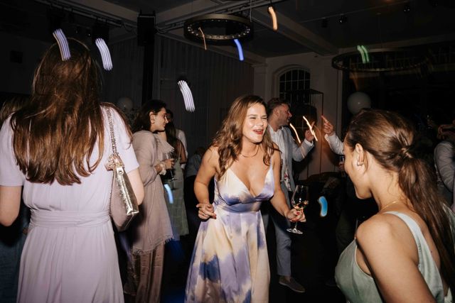 Guests dance and mingle on the dance floor with light trails captured in a long exposure.