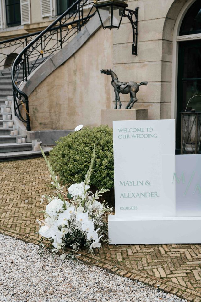 A welcome sign greeting guests by name stands at the entrance, framed by flowers.