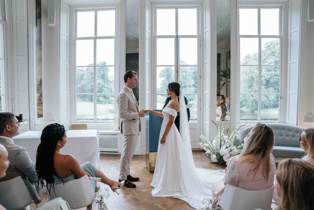 The couple stands hand in hand before the officiant during the ceremony.