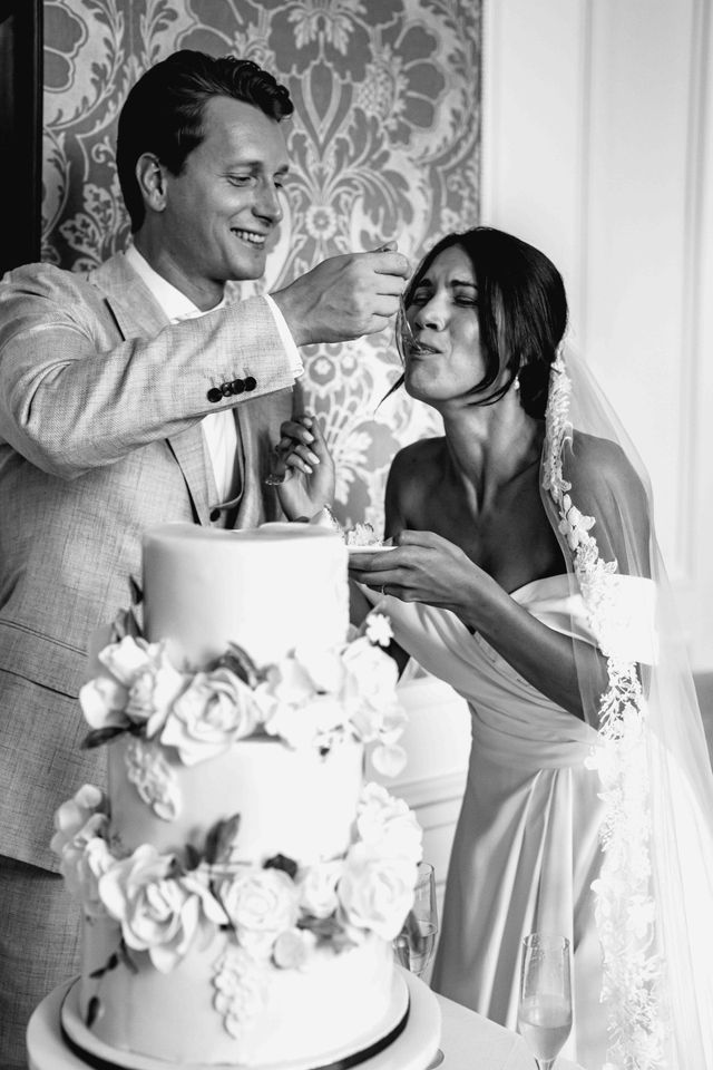 A black and white photo of the groom feeding the bride a bite.