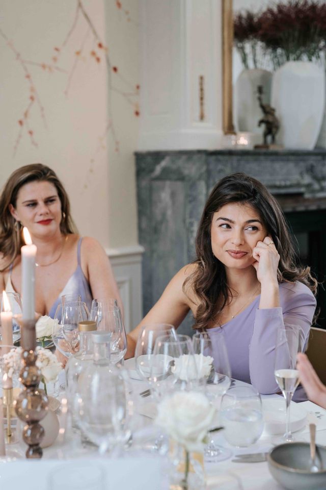 Two female guests in lilac dresses sit at the festively set table.