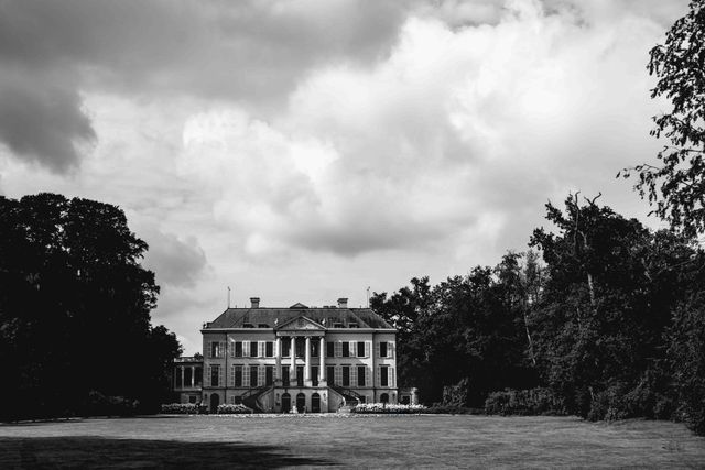 A black and white photo of a large classic manor house with columns.