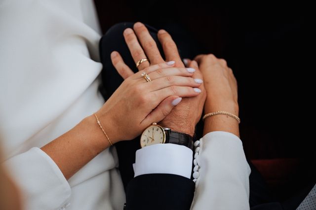 Couple's hands resting together showing their wedding rings