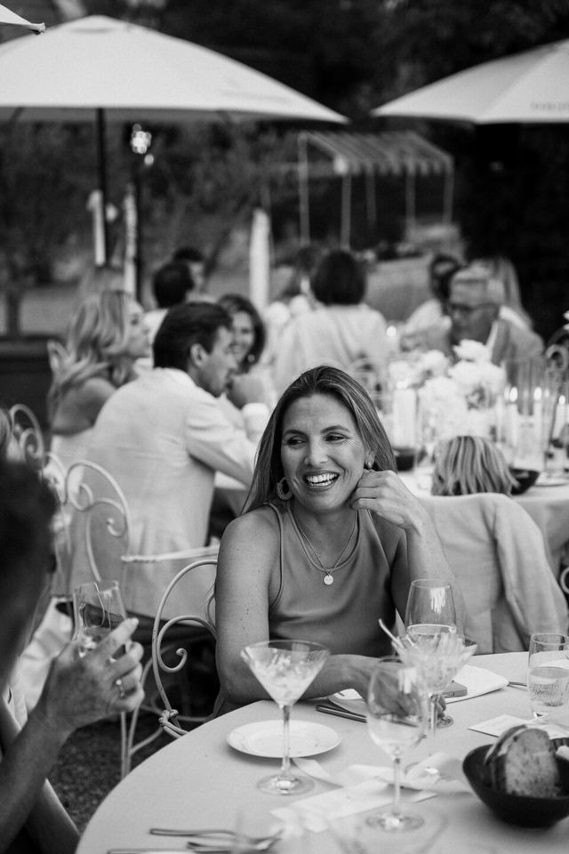 A black and white photo of a laughing female guest at the table.