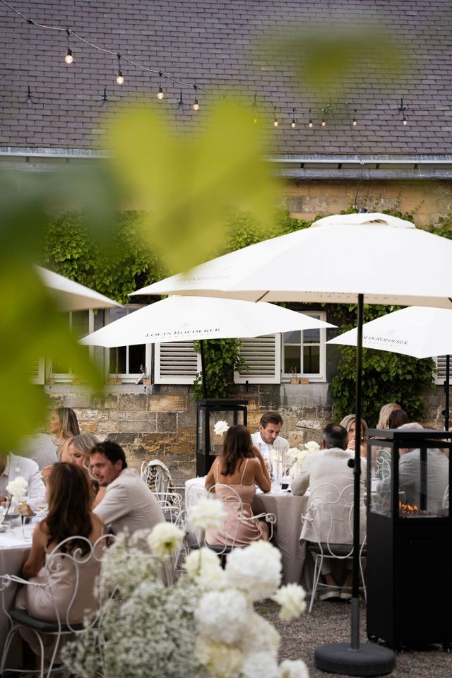 Guests dine under white parasols on a Mediterranean courtyard.