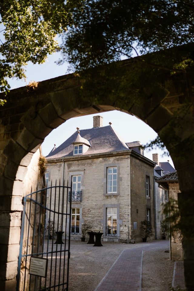 A view through a stone gate to a historic castle building with a white facade.