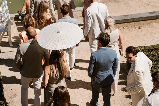 An overhead view of guests in light summer clothing gathering around a white parasol.