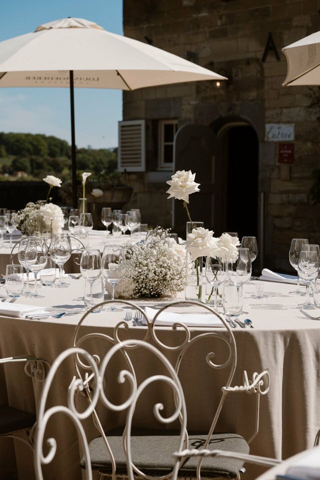 A round table set with white flowers and glassware under soft light.