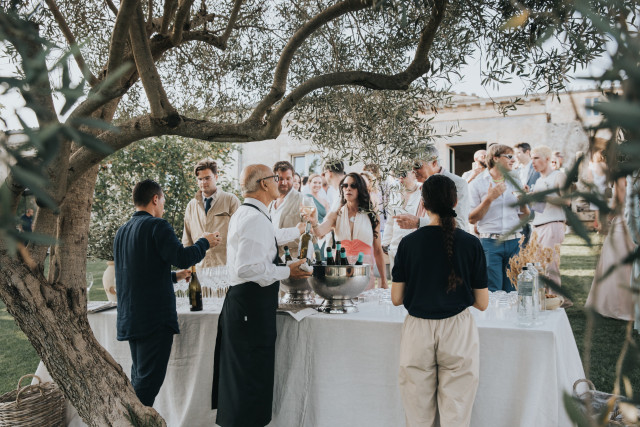 Guests gather around a styled drinks table with white florals at cocktail hour.