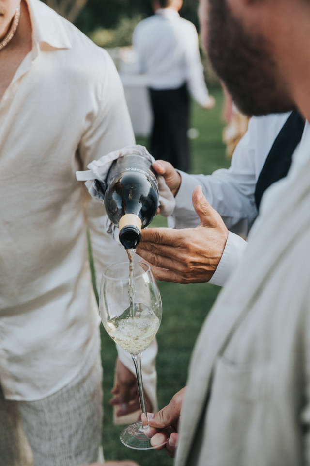 A detail of white wine being poured into a glass at the reception.