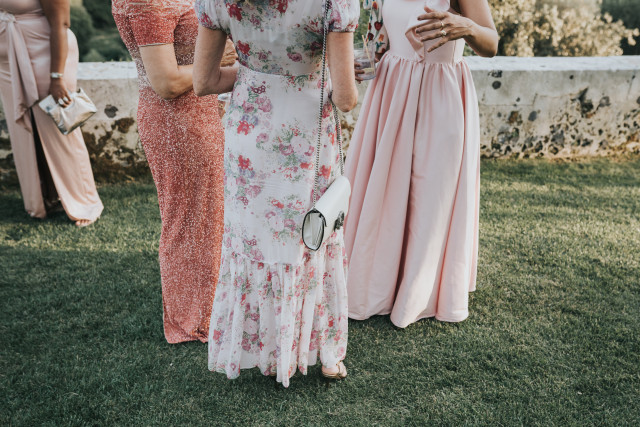 A detail of three guests in pastel and floral dresses at the celebration.