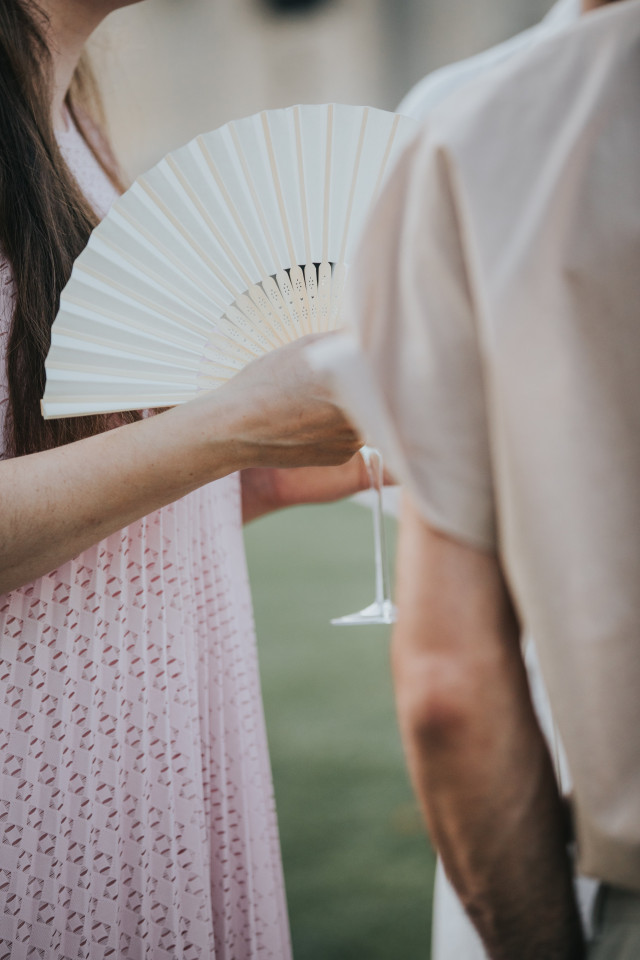 A detail of a guest in a pink dress with a white accessory.