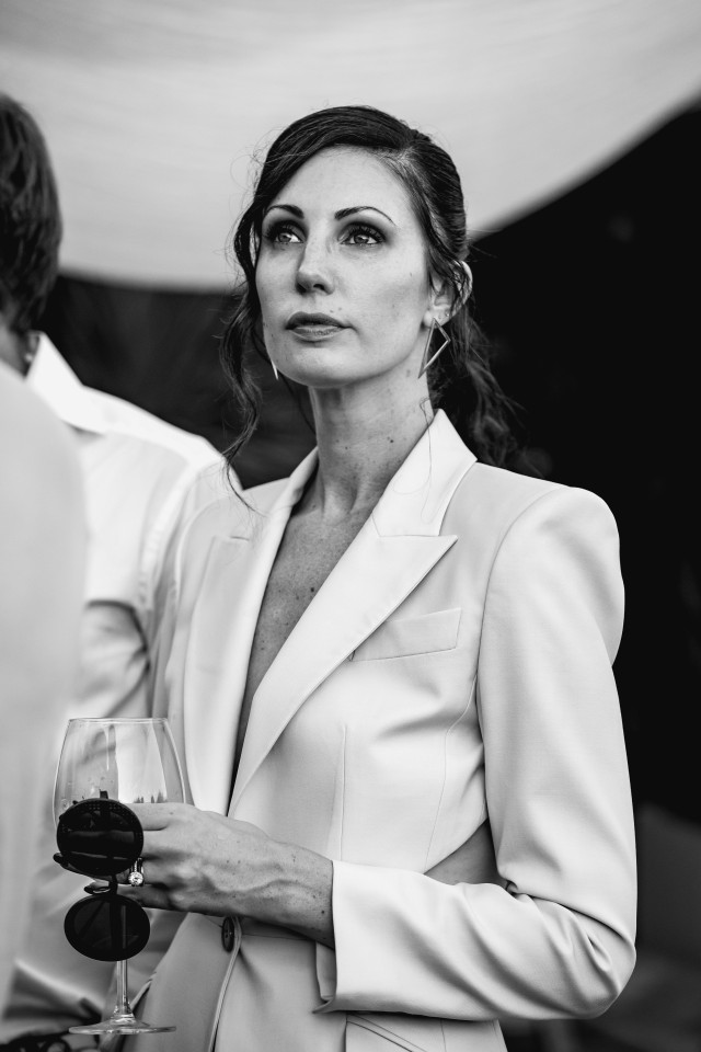 een vrouw in een wit pak die een glas vasthoudt