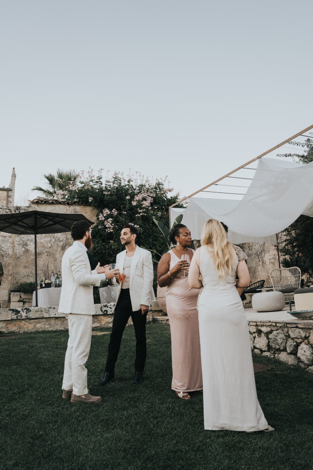 A group of festively dressed guests stands chatting at the reception.